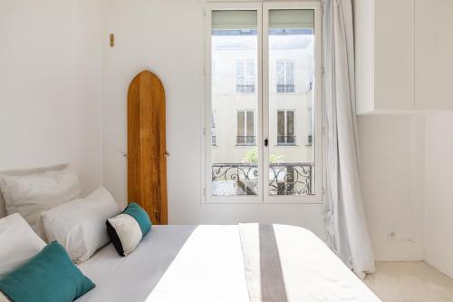 biała sypialnia z łóżkiem i oknem w obiekcie Exceptional Haussmannian apartment- Heart of Paris w Paryżu