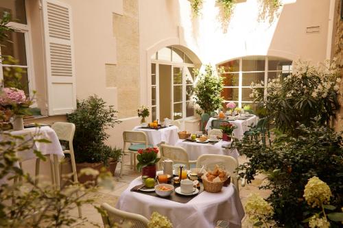巴黎的住宿－美迪西田園酒店，一间设有白色桌椅和鲜花的餐厅