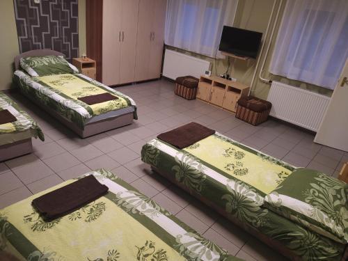 a room with three beds and a flat screen tv at Pingpong Apartman in Soltvadkert