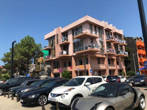 ein Parkplatz mit Autos, die vor einem Gebäude geparkt sind in der Unterkunft M-Rooms in Kobuleti