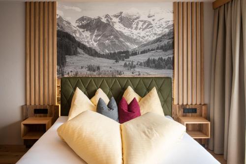 Hotel Königsleiten Vital Alpin في كونيغشليتن: سرير بمخدات عليها لوحة جبل