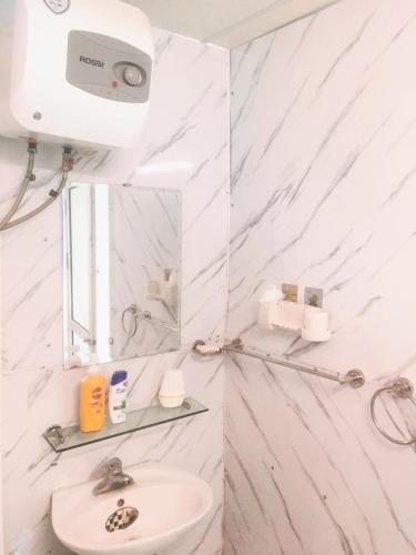 une salle de bain blanche avec un lavabo et un miroir dans l'établissement Hanowood Homestay, à Hanoï