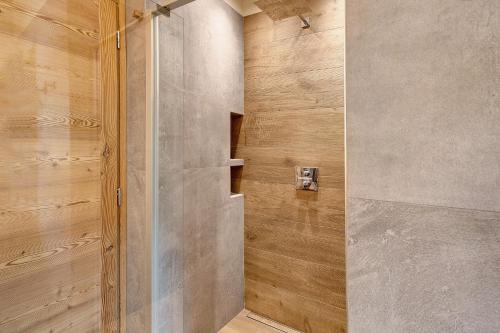 a walk in shower with a wooden wall at Aria di Casa Piazzi in Valdisotto