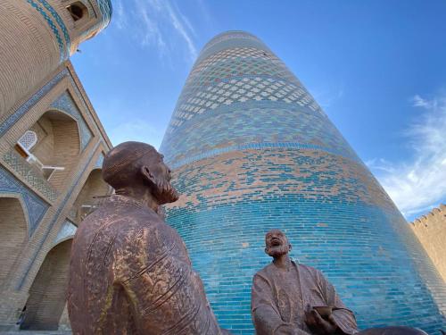 a statue of two men in front of a building at XIVA AZIM OTA in Khiva
