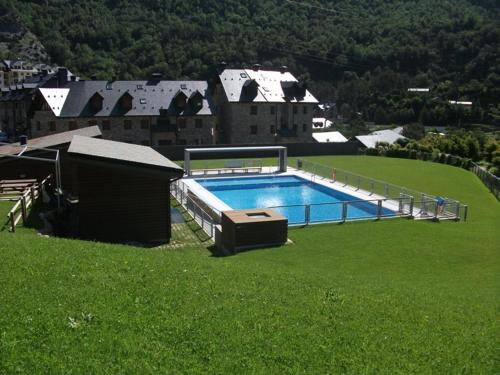 ein großer Pool auf einem grünen Rasen in der Unterkunft Alojamiento Escarrilla Pirineos in Escarrilla