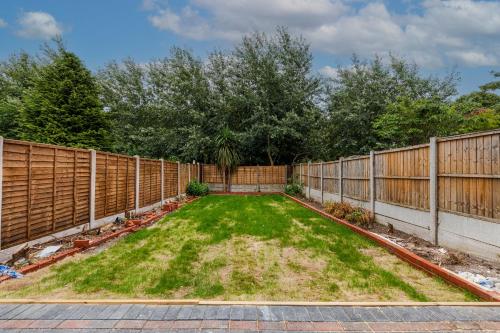 a backyard with a fence and a green yard at Walsall - 4 Bedroom House, Wi-Fi, Garden , Sleeps 8 - JRR Stays in Bescot