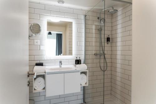 a white bathroom with a sink and a mirror at Appart'City Collection Genève Aéroport - Vernier in Geneva