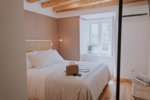 a bedroom with a white bed with a purse on it at CasadoRioHotel in Constância