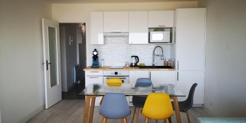 a kitchen with a table and yellow chairs at Appt entier Résidence de la Plage Vue Mer Port Navalo in Arzon
