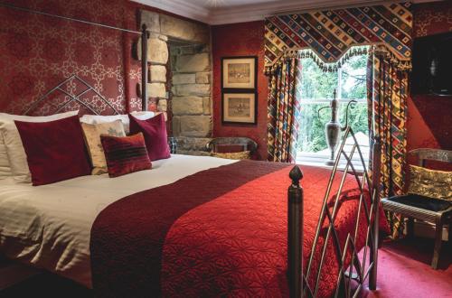 a bedroom with a large bed with red walls at Crab Manor Hotel in Thirsk