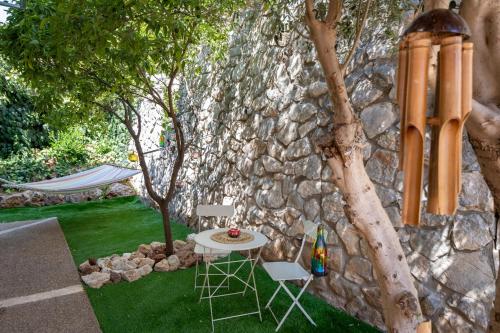 a table and chairs next to a stone wall at ירוק באלה - דירת נופש ברמת ישי in Ramat Yishay