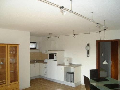 una cocina con armarios blancos y una mesa en una habitación en Ferienwohnung Erika, en Grenzach-Wyhlen