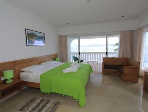 a bedroom with a bed with a green blanket at Marie-France Beach Front Apartments in La Digue