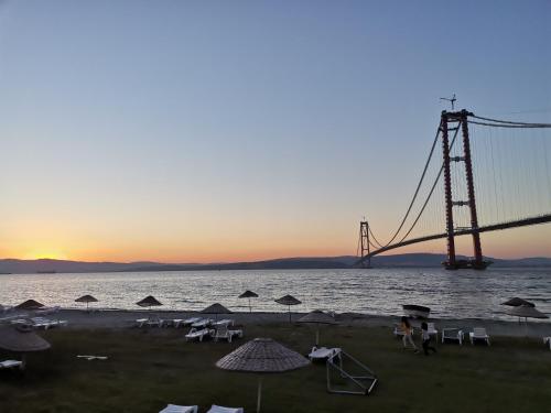 a bridge with chairs and umbrellas in front of the water at 1915 Çanakkale Köprü manzarali 700m2 bahceli mustakil ev in Canakkale