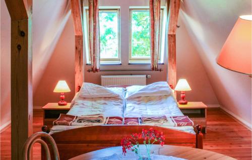 a bedroom with a bed with two tables and two windows at Cozy Home In Lebcz With Kitchen in Łebcz