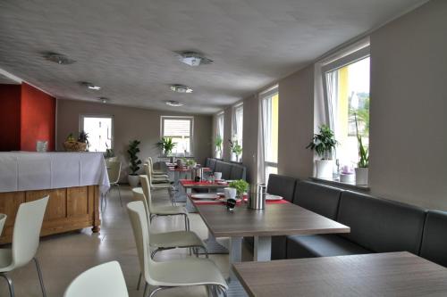 uma sala de jantar com mesas, cadeiras e janelas em Apado-Hotel garni em Homburg