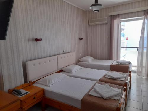 een kamer met 2 bedden en een raam met bij Phaethon Hotel in Kos-stad