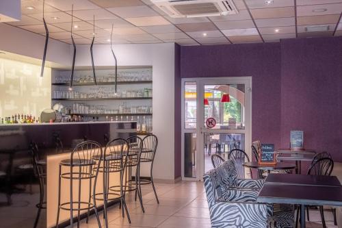 a restaurant with chairs and a bar with purple walls at The Originals City, Hôtel Les Thermes de l'Avenue, Dax in Dax