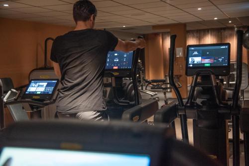 a man exercising in a gym with two monitors at Arken Hotel & Art Garden Spa in Gothenburg