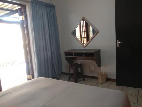 a bedroom with a bed and a desk and a mirror at Ebeneezer Self-Catering Guesthouse in the Lowveld in Sabie