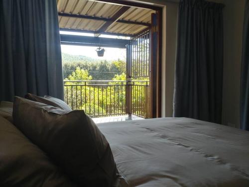 a bedroom with a bed and a large window at Ebeneezer Self-Catering Guesthouse in the Lowveld in Sabie