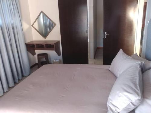 a bedroom with a large white bed with a black door at Ebeneezer Self-Catering Guesthouse in the Lowveld in Sabie