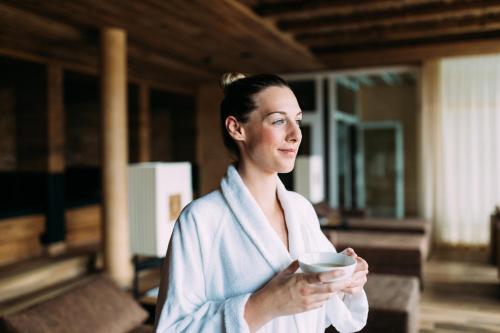 a woman in a bathrobe holding a bowl at Alpin Resort Sacher in Seefeld in Tirol