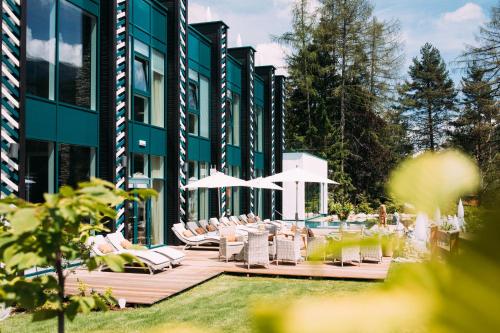 a building with a deck with chairs and a pool at Alpin Resort Sacher in Seefeld in Tirol