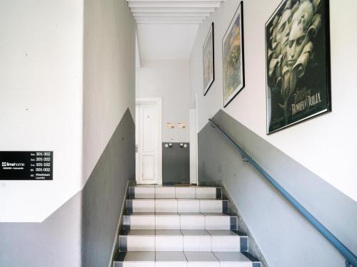 a stairway with a white wall and some framed pictures at Limehome Dresden Antonstraße in Dresden