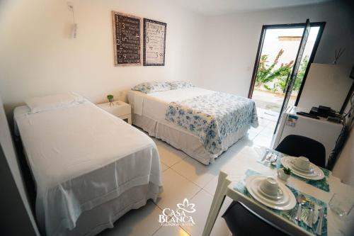a bedroom with two beds and a table and a mirror at Casa Blanca in Galinhos