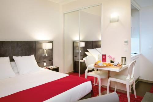 a hotel room with a bed and a table and chairs at Appart'City Confort Grenoble Inovallée in Montbonnot-Saint-Martin