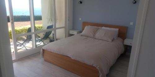 uma cama com 2 almofadas num quarto com uma varanda em Appt entier Résidence de la Plage Vue Mer Port Navalo em Arzon