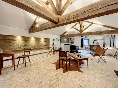 a living room with wooden ceilings and tables and chairs at Magnifique et confortable loft in Marlieux