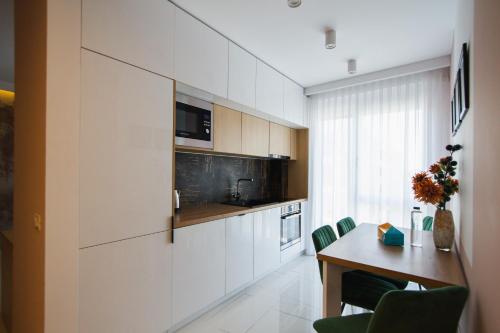 a kitchen with white cabinets and a table with green chairs at Romantic getaway at West Residence in Oradea