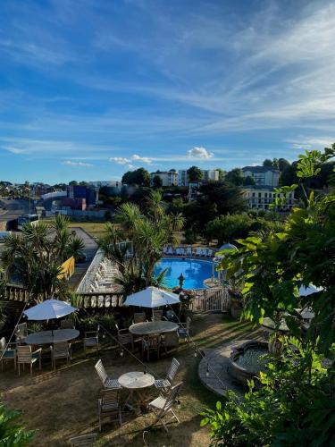a view of a swimming pool with tables and umbrellas at Livermead House Hotel in Torquay