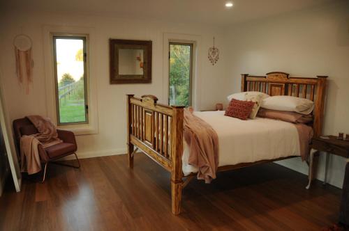 een slaapkamer met een houten bed en een raam bij Wagtail Nest Country Retreat - Longford Vic 3851 in Sale