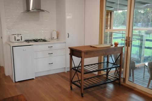 een keuken met een houten tafel en een aanrecht bij Wagtail Nest Country Retreat - Longford Vic 3851 in Sale