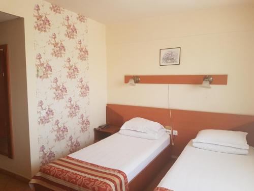 2 Betten in einem Zimmer mit Blumen an der Wand in der Unterkunft Hotel Transit in Oradea