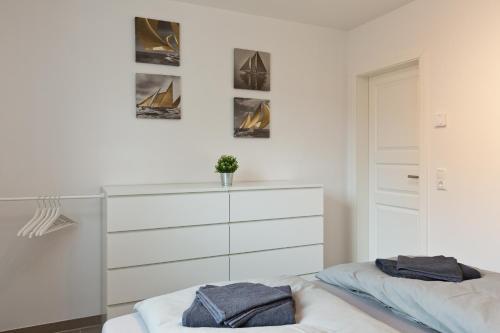 een witte slaapkamer met 2 bedden en een dressoir bij Apartment unter den Kiefern 109 in Röbel