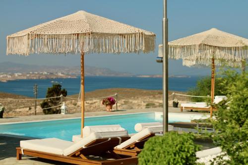 a swimming pool with two umbrellas and two lounge chairs at Blue Bay Heliolithos in Parikia