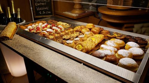 a display case with a bunch of donuts and pastries at Folgaria Post Hotel in Folgaria
