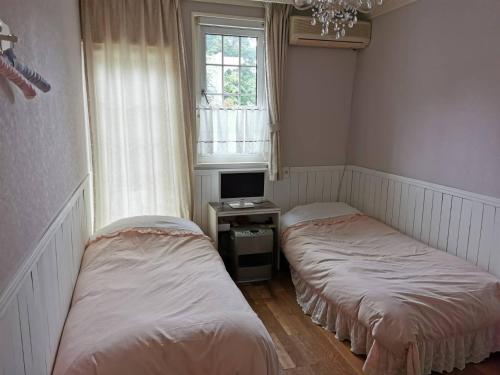 two beds in a room with a tv and a window at Kitasaku District - Hotel - Vacation STAY 89259 in Kutsukake