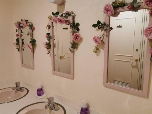 a bathroom with two sinks and two mirrors with flowers at Kitasaku District - Hotel - Vacation STAY 89259 in Kutsukake