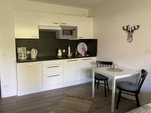 eine Küche mit weißen Schränken und einem Tisch mit Stühlen in der Unterkunft Fewo Lotte in Goslar