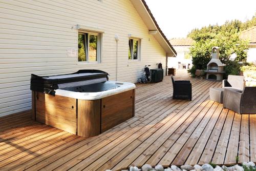 einen Whirlpool auf einer Terrasse neben einem Haus in der Unterkunft LE CHALET BLANC - JACUZZI / PISCINE / SAUNA in Gérardmer