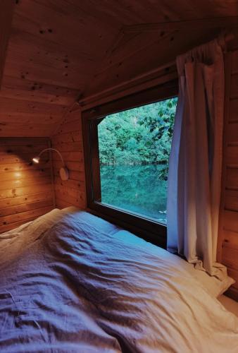 a bedroom with a window in a log cabin at Riverland in Gornji Zvečaj