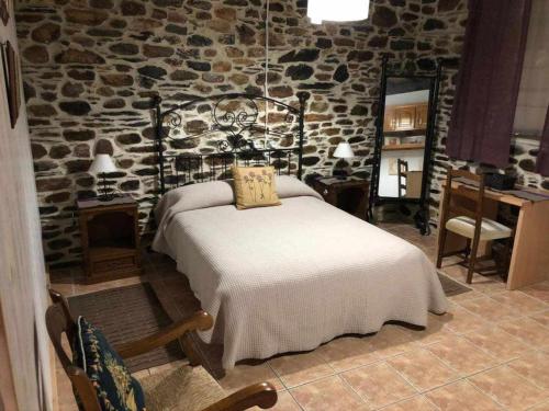 een slaapkamer met een bed en een stenen muur bij Casa do Hiebra Alojamiento Rural Ribeira Sacra 