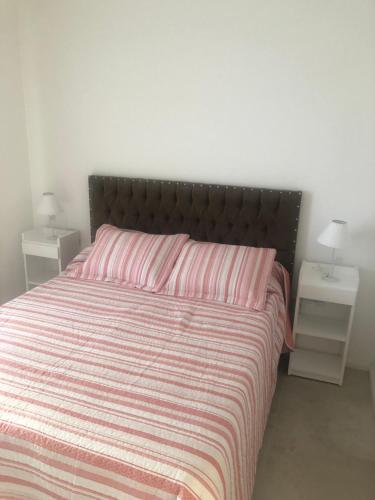 a bedroom with a bed with a striped bedspread and a night stand at Depto More III in Puerto Madryn