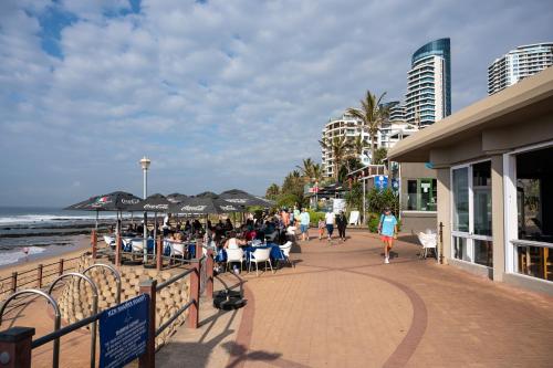 a crowd of people walking on a boardwalk near the beach at Oceans Umhlanga Accommodation in Durban