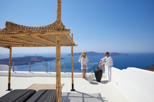 a bride and groom sitting on the edge of a roof with the ocean at U & ME SUITES in Fira